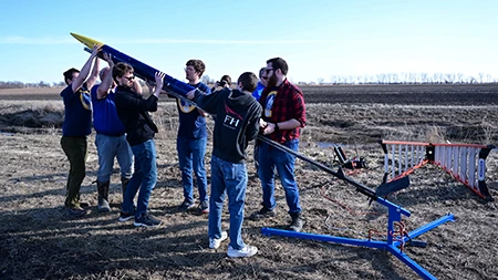 Small group of students and professors setting up rocket