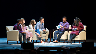 A group of students discusses on stage