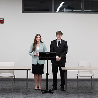 two forensics students standing behind a podium