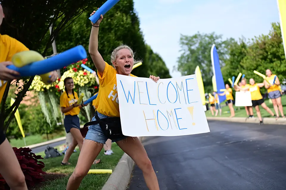 Girl yelling and holding welcome home sign