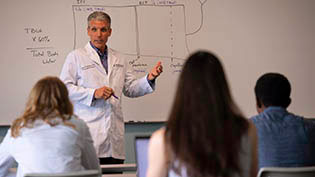 Group of doctors in white lab coats reviewing information on a whiteboard.