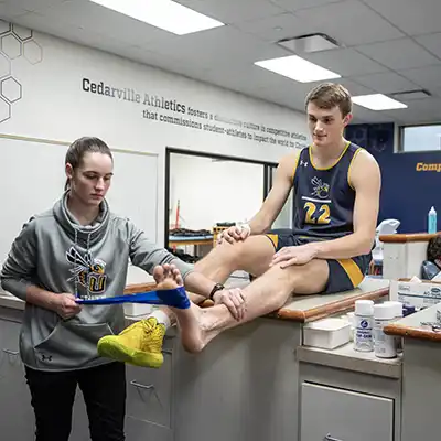 student athletic trainer treating athlete.