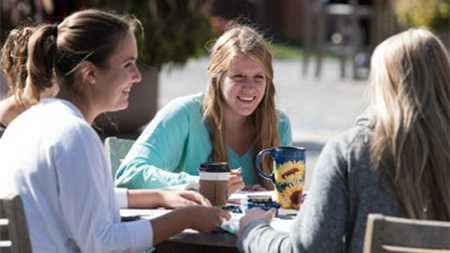 Female students studying at outdoor table on a patio.