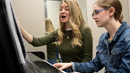 Female students playing piano and singing.