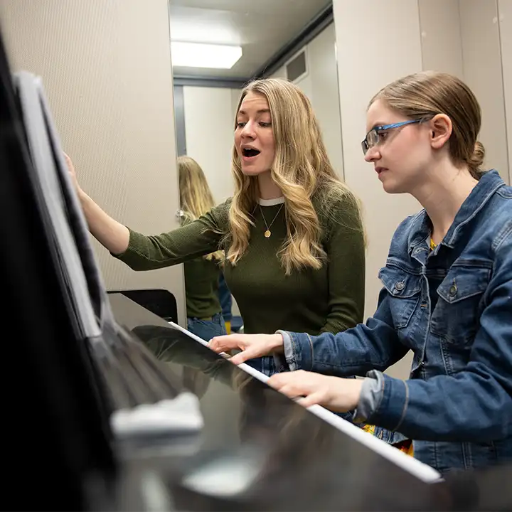 Female students playing piano and singing.