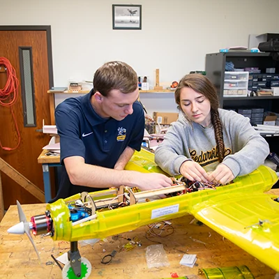Students working on a large semi-transparent remote controlled electric propeller driven aircraft.