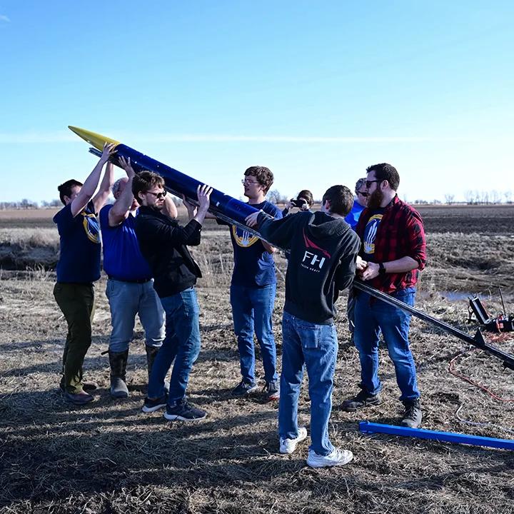 Small group of students and professors setting up rocket