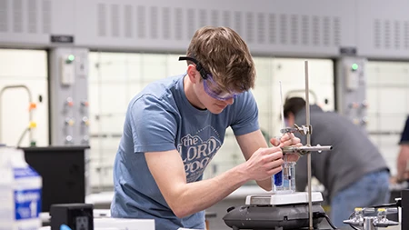 Male student working with equipment in a science laboratory.