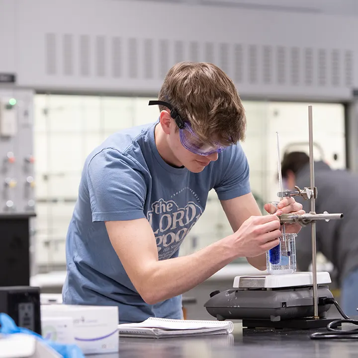 Male student working with equipment in a science laboratory.