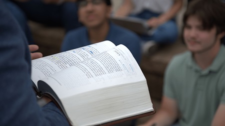 closeup of professor holding an open Bible while lecturing in class