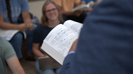 closeup of professor holding an open Bible while lecturing in class