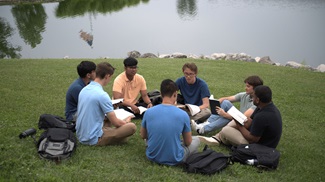 group of male students having an outdoor Bible study in the grass