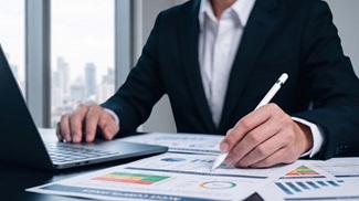 Man in office looking over charts and financial reports on his desk.