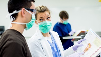 premedical student and professor looking at human anatomy textbook
