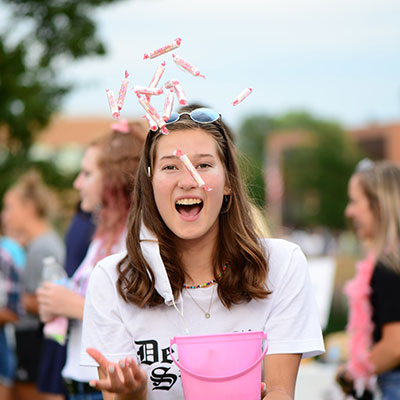 Female student tossing candy in celebration.