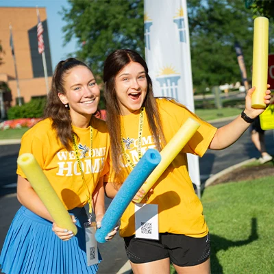 Two girls wearing Welcome Home shirts and cheering.