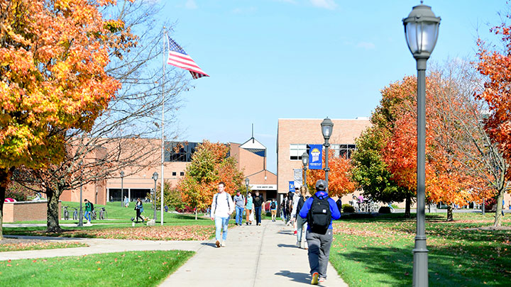 Sunny autumn day, students walking on a sidewalk.