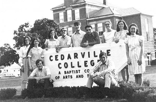Cedarville students standing around a Cedarville College sign. Black and white from 1972.
