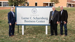 Photo of Lorne Scharnberg, his son and Dr. White next to a sign promoting the new Business Center.