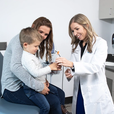 Nurse smiling and talking with a mother and son in doctor's office room