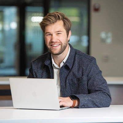Graduate college student smiling while working on laptop computer