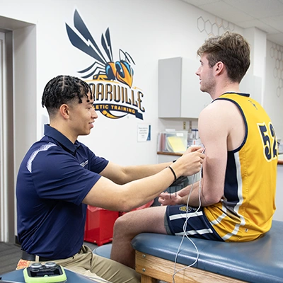Athletic training graduate student treating basketball player