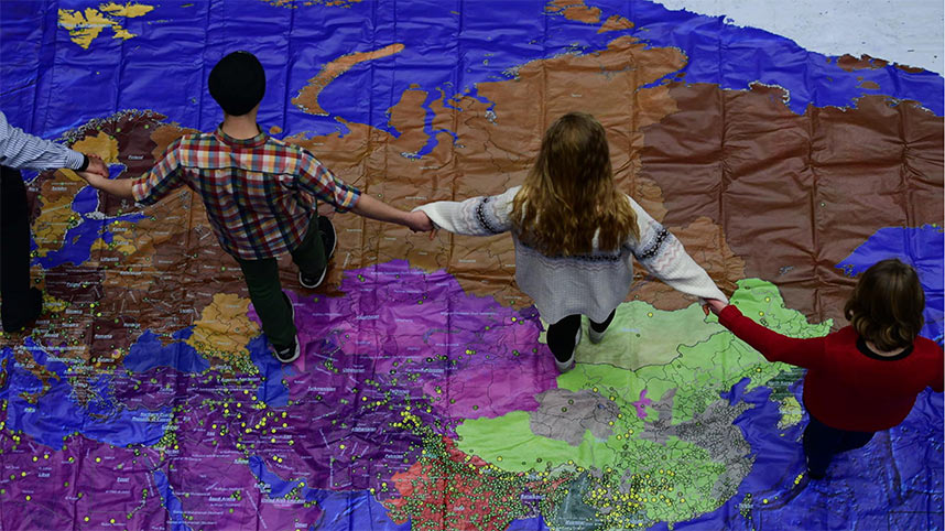 Students standing and praying on top of a map of the world