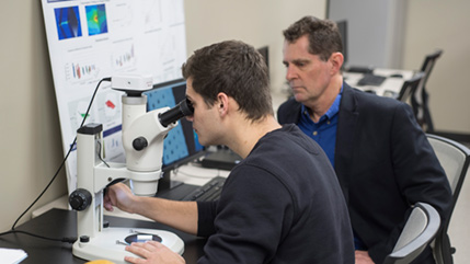 Biomedical engineering student looks at 3D printing structure through microscope