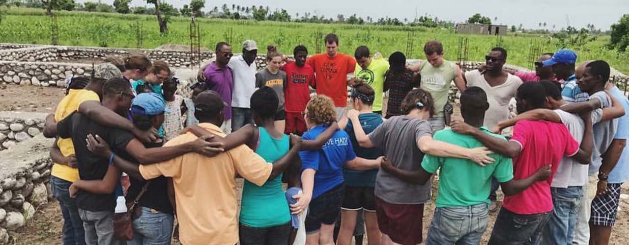 Haiti mission team prays in circle with Haitians