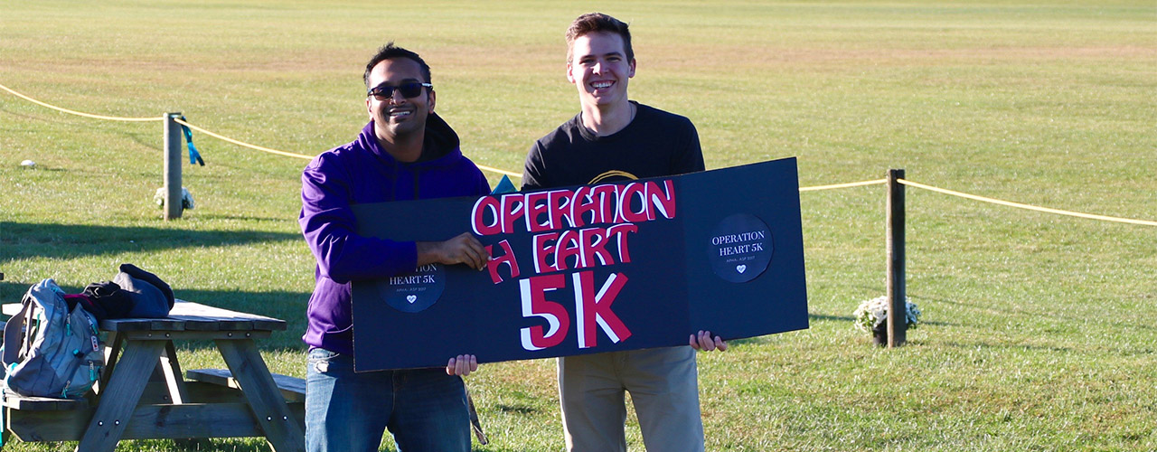Two young men holding Operation Heart 5K sign