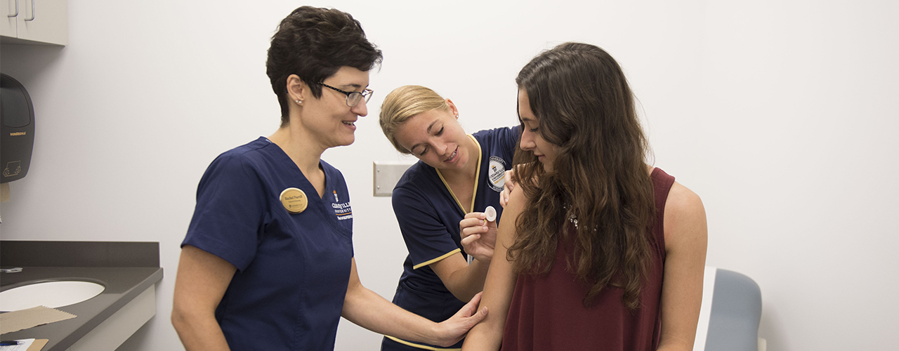 Cedarville student vaccinates another student, with a preceptor's assistance