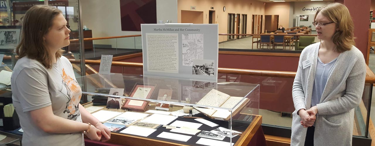 Students discussing Martha McMillan journals at Centennial Library display