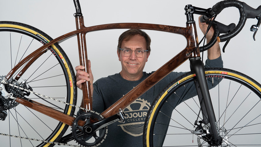 Prof. Jay Kinsinger holding a Sojourn Cyclery wooden bike