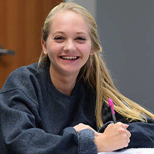 Student smiling and holding a pen