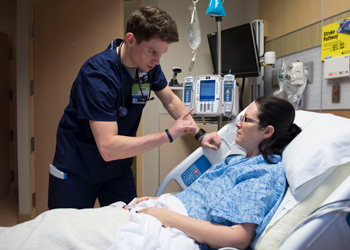 Nursing student working with patient in a hospital room