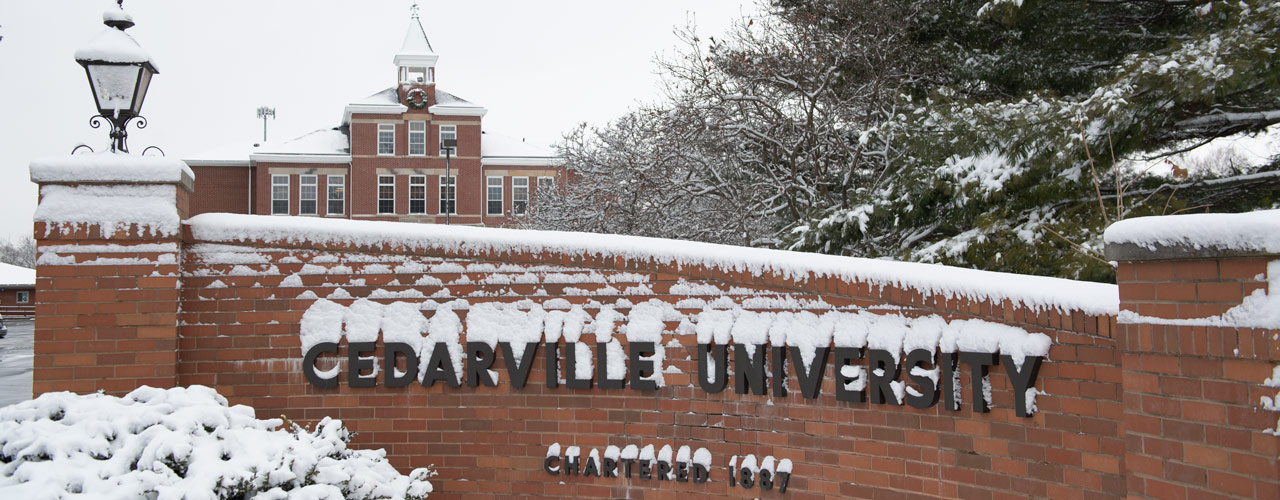 Snowy Cedarville University sign out by St. Rt. 72 with Founders Hall in the background