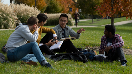 Students discussing the Bible while sitting on the grass