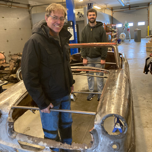 Prof. Jay Kinsinger and student standing inside the body of a Nash Rambler