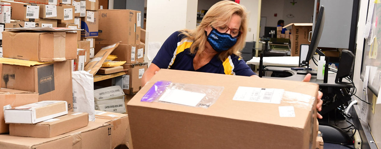 Cedarville University post office worker lifts a box