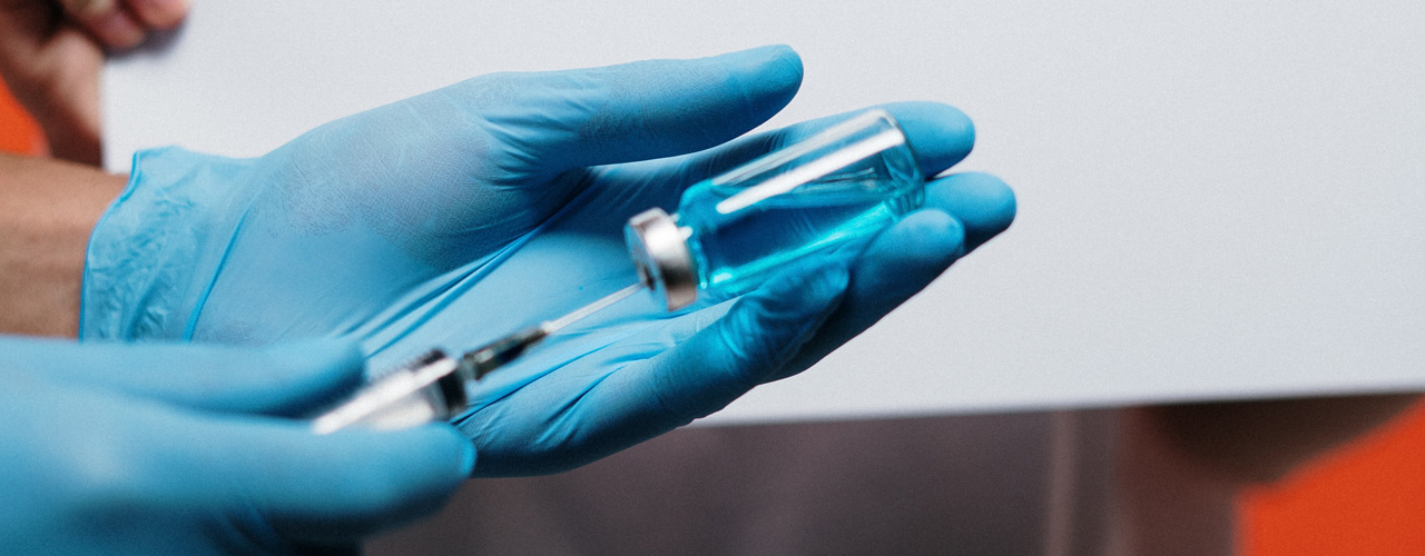 Syringe and vile of medicine in blue gloved hand