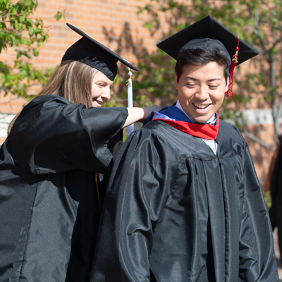 Student fastening graduate hood
