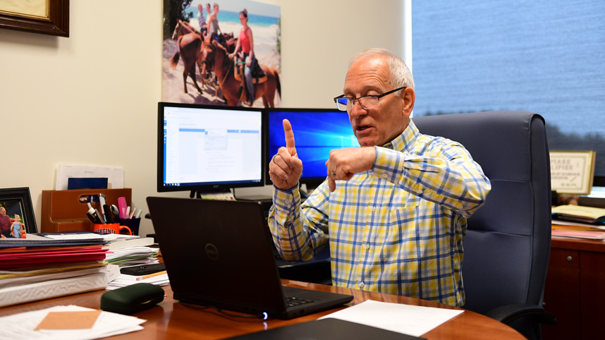 Professor Mark Klimek talking with a student on his laptop computer