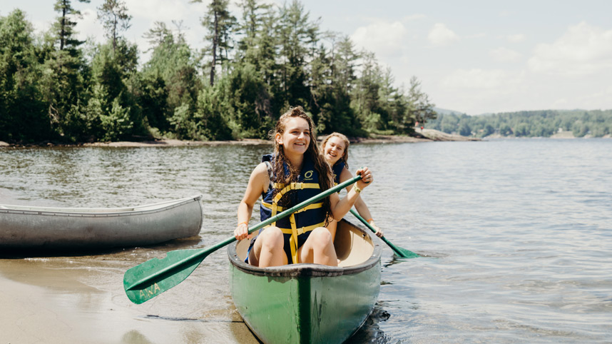 Two teenage girls paddling a canoe