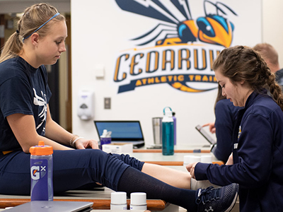 Athletic training student wrapping a student-athlete's ankle