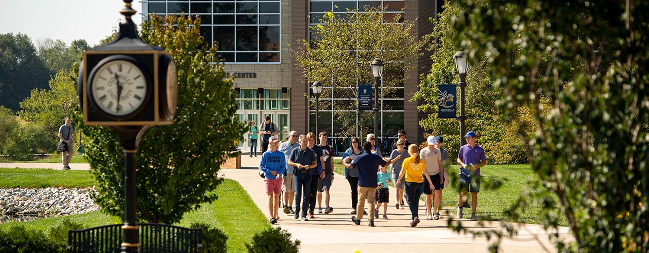 Admissions tour guides walk a group between the health sciences center and Stevens Student Center.