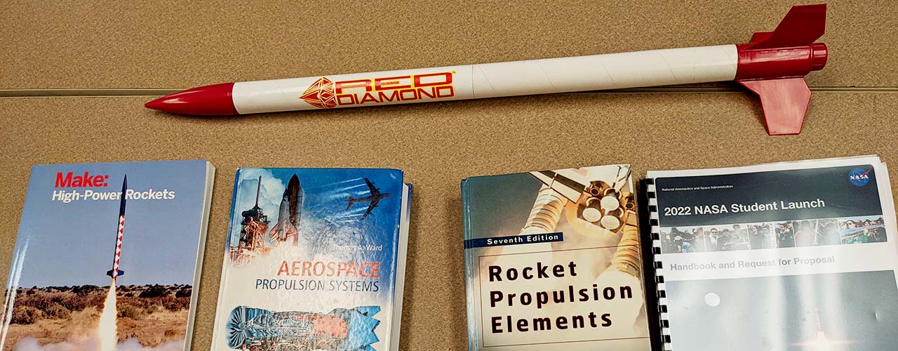 A toy rocket and four books on rocketry