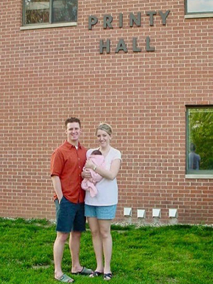 Courtenay and Jason Atwell hold their daughter, Kylie, outside of Printy Hall, where Courtenay served as residence director from 2001-2003.