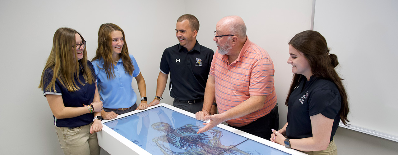 Dr. Ken Blood, associate professor of athletic training, demonstrates the Anatomage Table to a group of students.