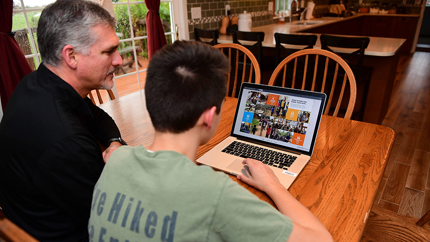 Mark Mazelin, director of web services, reviews the Cedarville online catalog with his son, Austin