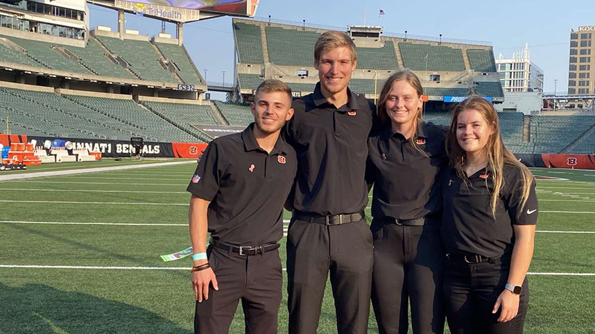 Senior athletic training student Kurtis Gould, second from left, standing on the football field at Paul Brown Stadium